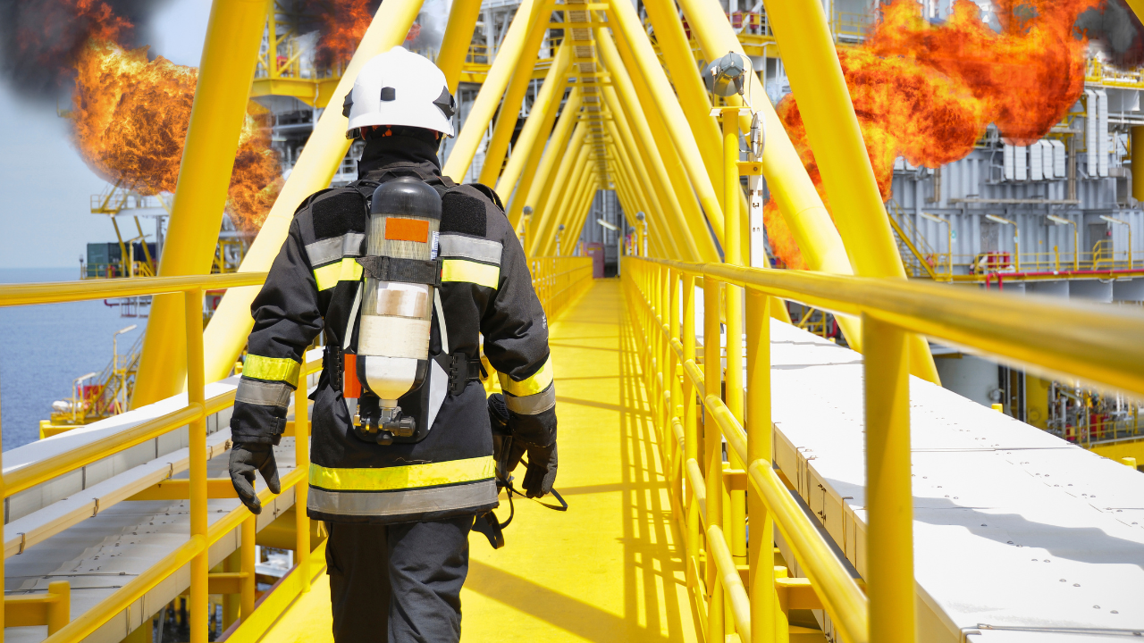 industrial firefighter walks across an elevated path towards a fire