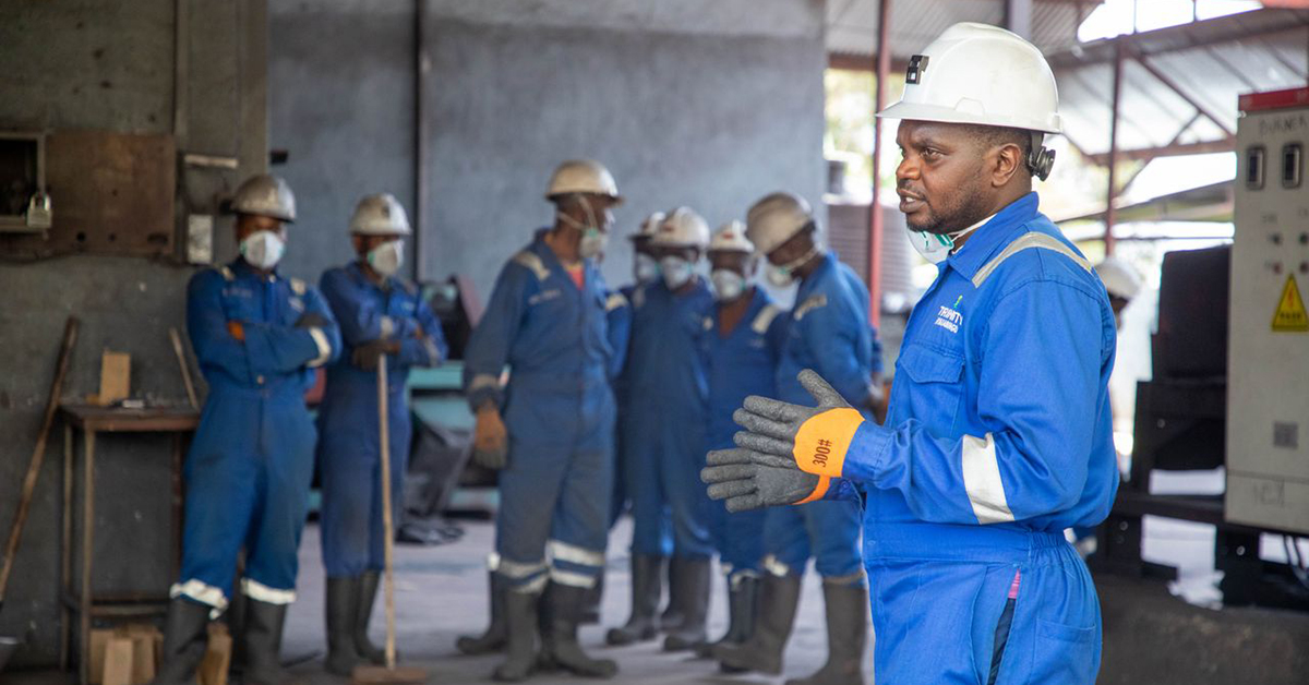 Plant workers in hard hats and coveralls gathered at a muster point during an emergency headcount